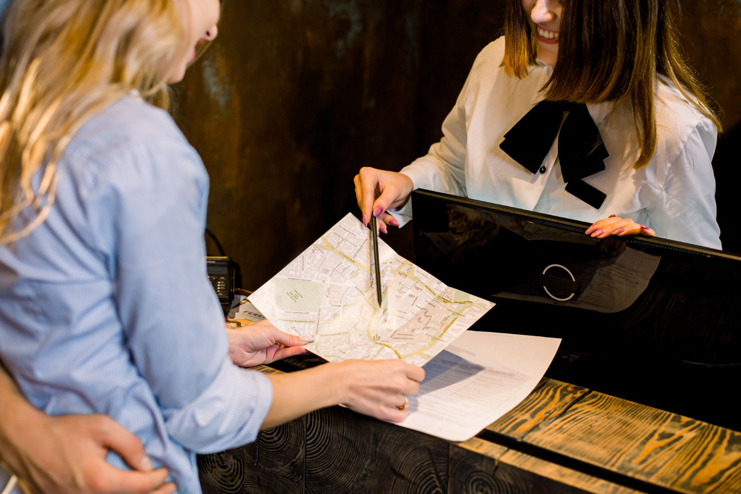 Traducciones expertas sector hotelero, recepcionista explicando mapa en idioma del cliente